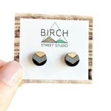 A pair of round wooden earrings with a black and grey chevron pattern.