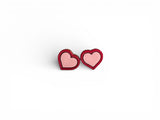 A pair of heart shaped wooden earrings painted pink with a red border. The earrings are very cute, small and minimalist style.
