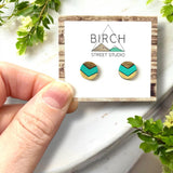 A pair of round dark wood earrings, hand painted with a mint green and gold chevron pattern.