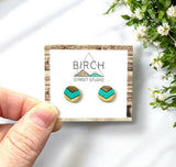 A pair of round dark wood earrings, hand painted with a mint green and gold chevron pattern.